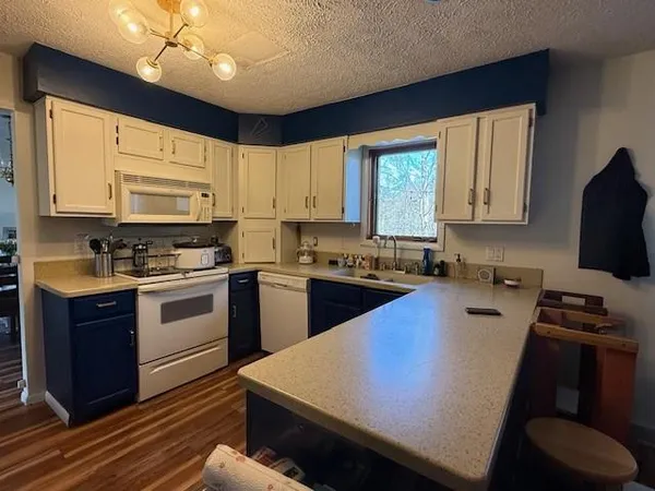 a kitchen with a stove a sink a microwave a refrigerator cabinets and wooden floor