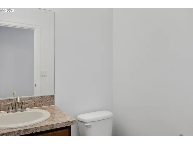 a bathroom with a granite countertop toilet and a sink