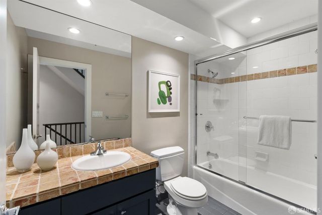 a bathroom with a granite countertop sink a toilet a mirror and shower