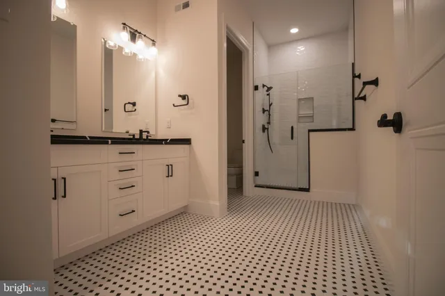 a bathroom with a granite countertop sink a mirror and shower