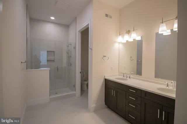 a bathroom with double vanity sink a shower and a mirror
