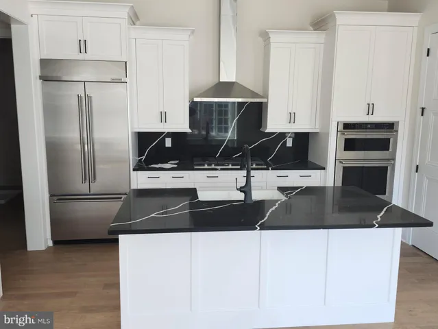 a kitchen with granite countertop a refrigerator a stove a microwave and white cabinets