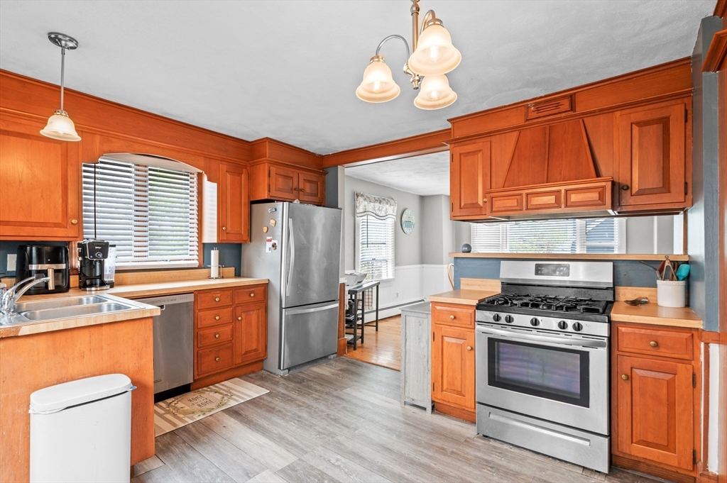 42 Chase Street Danvers, MA 01923 - Photo 8 of 37 a kitchen with stainless steel appliances granite countertop a refrigerator a stove a sink dishwasher and a dining table with wooden floor