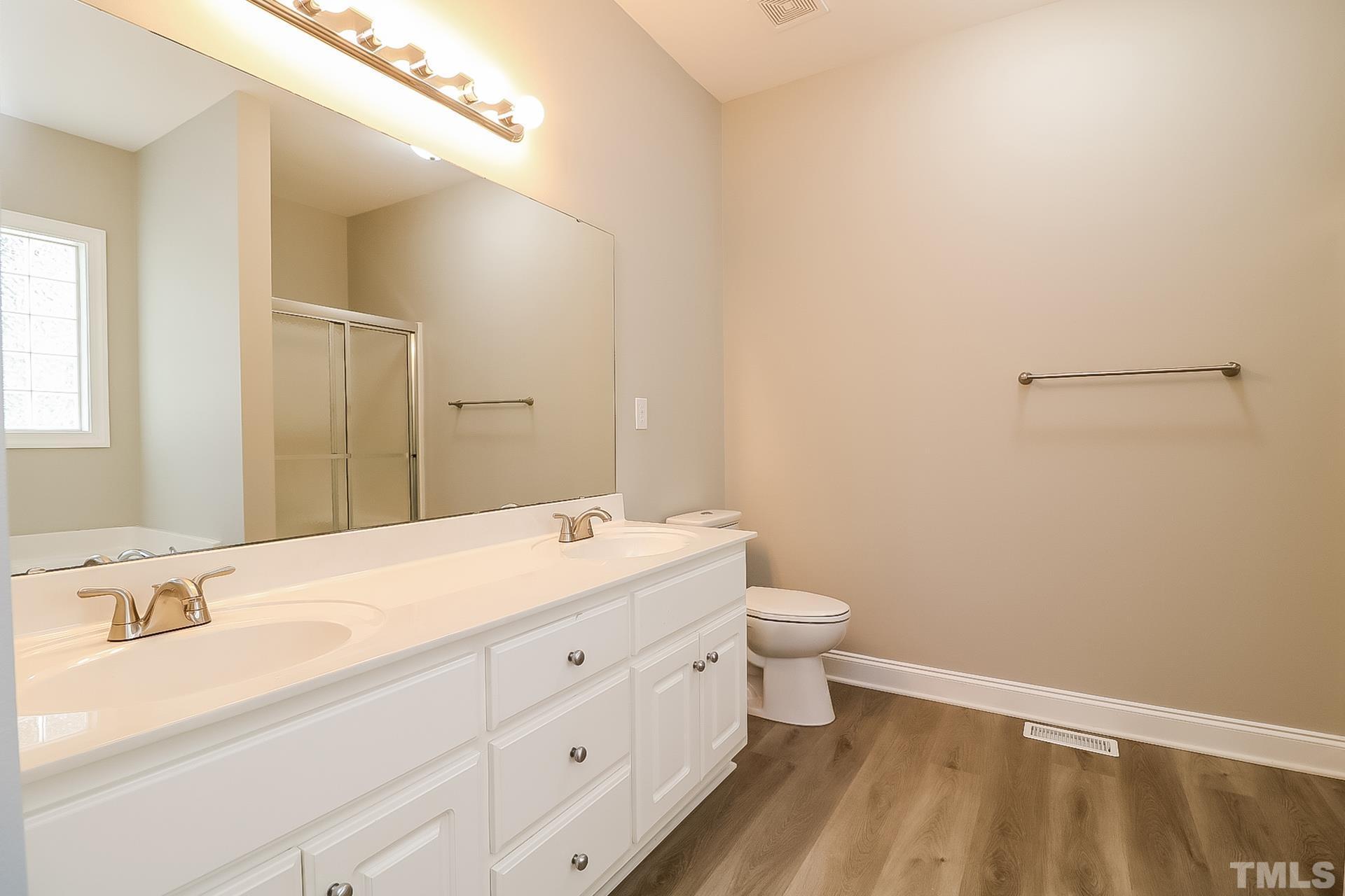 98 Moonlight Drive Garner, NC 27529 - Photo 12 of 17 a bathroom with a double vanity sink toilet and a mirror