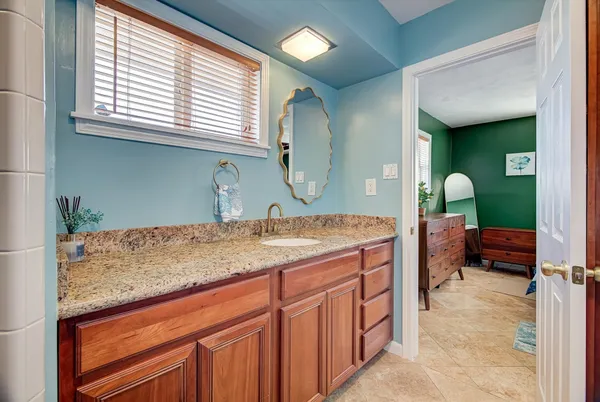 a bathroom with a granite countertop sink and a mirror