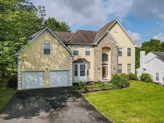 a view of a big house with plants and large trees with wooden fence