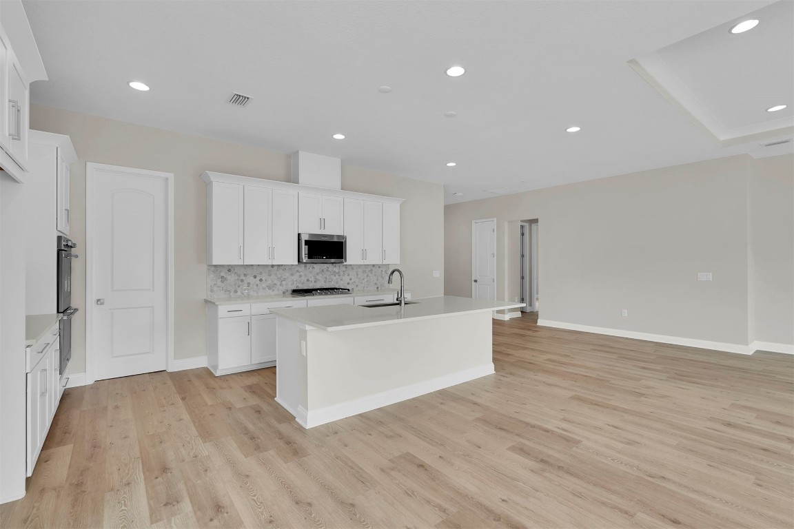 323 Sawgrass Drive Yulee, FL 32097 - Photo 17 of 33 a large white kitchen with white cabinets and wooden floor
