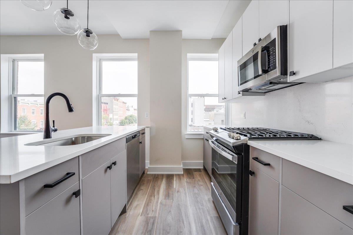 a kitchen with stainless steel appliances granite countertop a sink a stove and a microwave