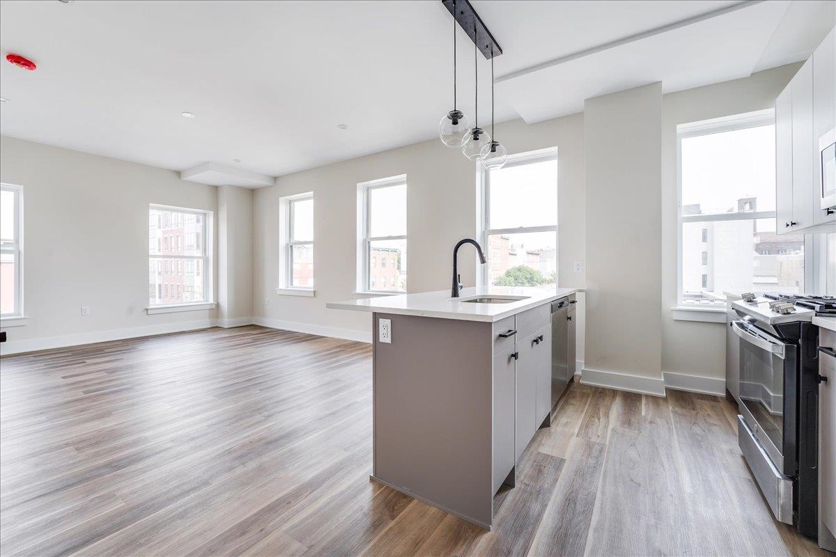 237 Washington Street, Unit 402 Hoboken, NJ 07030 - Photo 2 of 36 a kitchen with kitchen island granite countertop a sink appliances cabinets and a large window