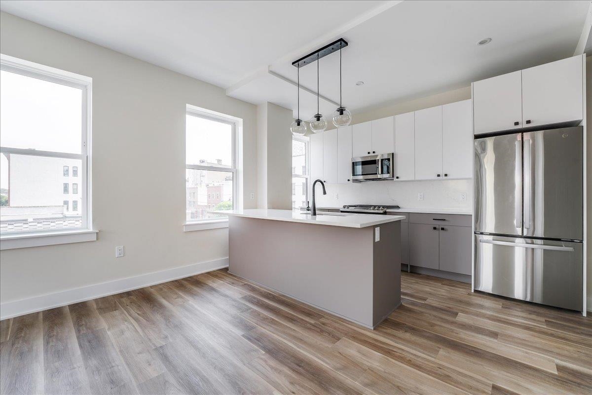 237 Washington Street, Unit 402 Hoboken, NJ 07030 - Photo 3 of 36 a kitchen with stainless steel appliances granite countertop a refrigerator a stove a sink and white cabinets with wooden floor