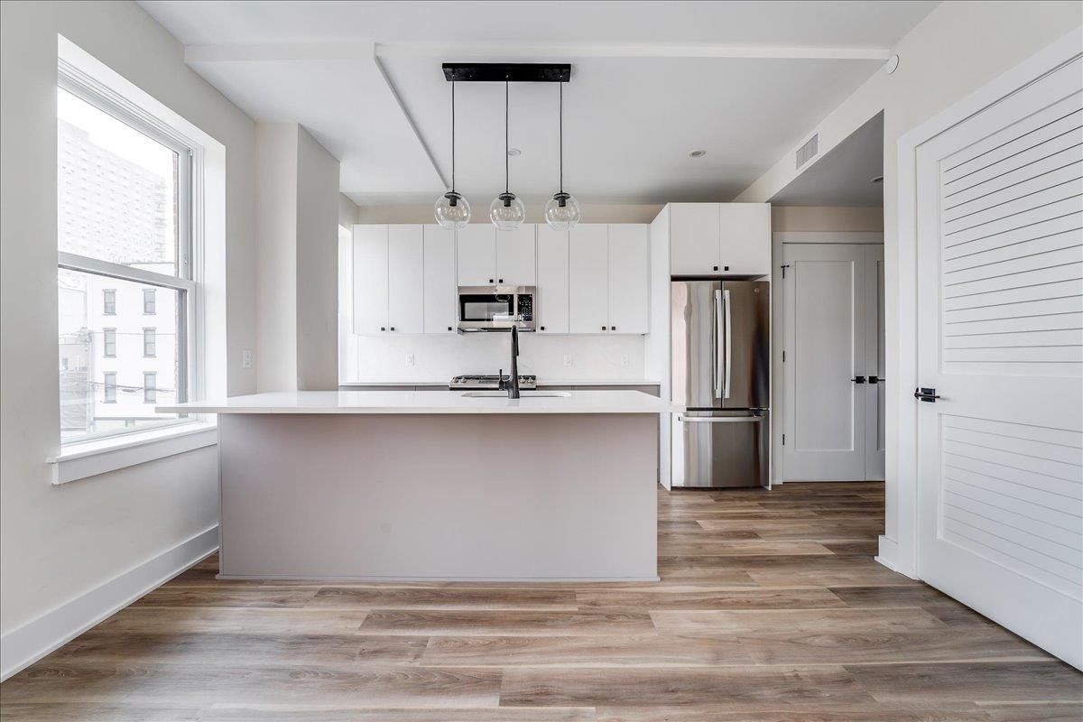 237 Washington Street, Unit 402 Hoboken, NJ 07030 - Photo 4 of 36 a kitchen with stainless steel appliances granite countertop a refrigerator a sink dishwasher a stove and white cabinets with wooden floor