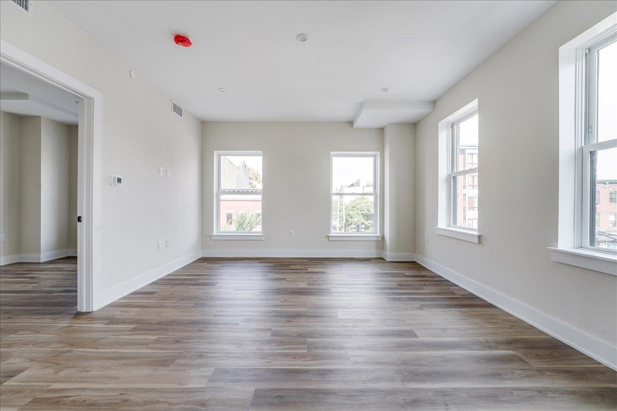 237 Washington Street, Unit 402 Hoboken, NJ 07030 - Photo 6 of 36 an empty room with wooden floor and windows