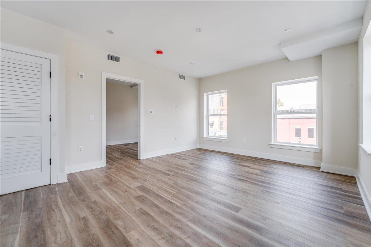 237 Washington Street, Unit 402 Hoboken, NJ 07030 - Photo 7 of 36 an empty room with wooden floor and windows