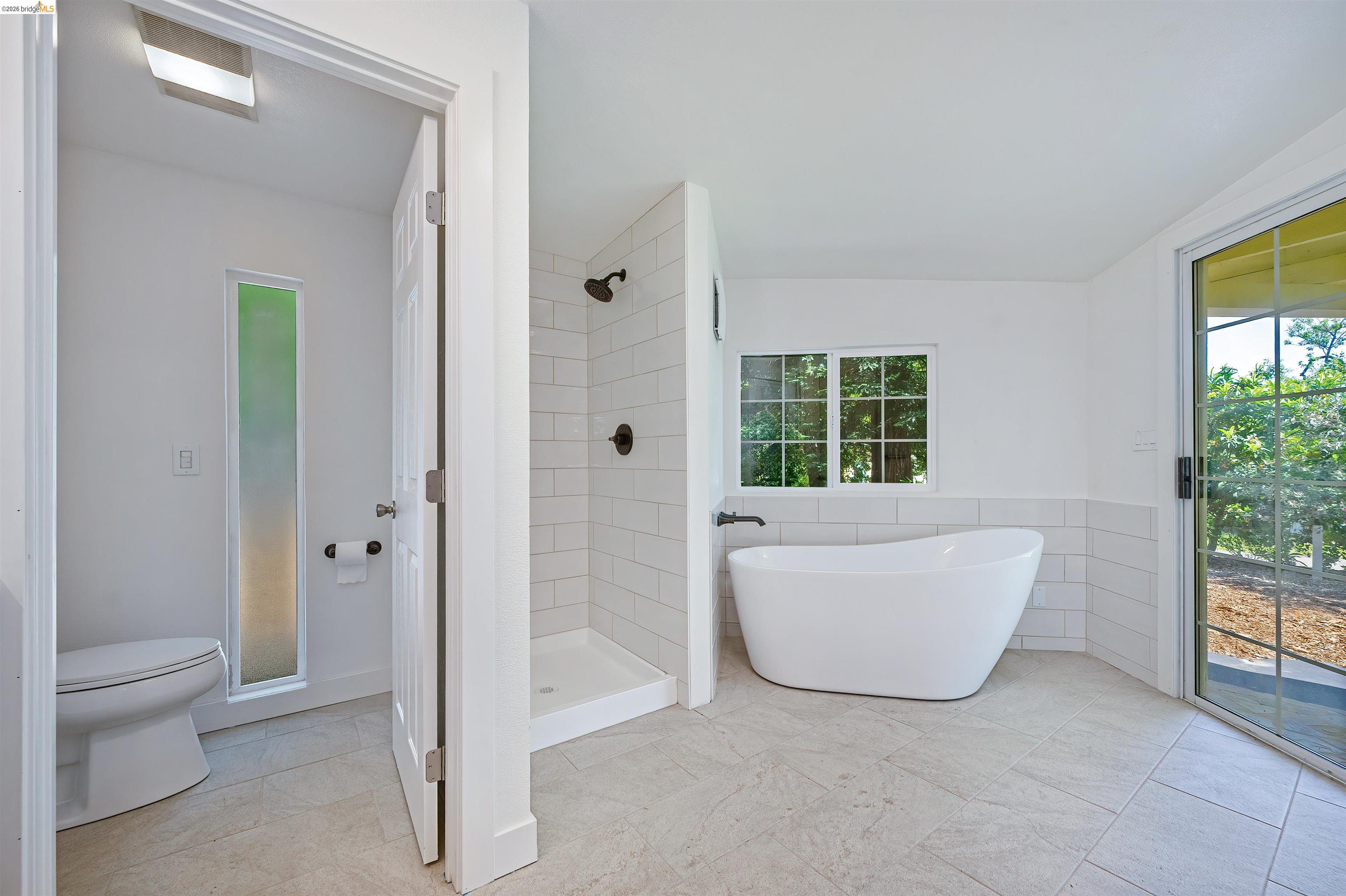 10474 Sheldon Road Elk Grove, CA 95624 - Photo 31 of 83 Bathroom featuring a freestanding soaking tub, a separate shower with subway tile surround and dark bronze fixtures, and light-toned tile flooring