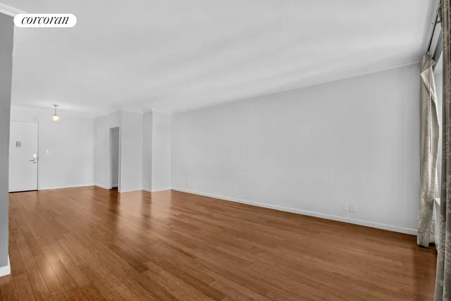 a living room with furniture and flowers on table with wooden floor