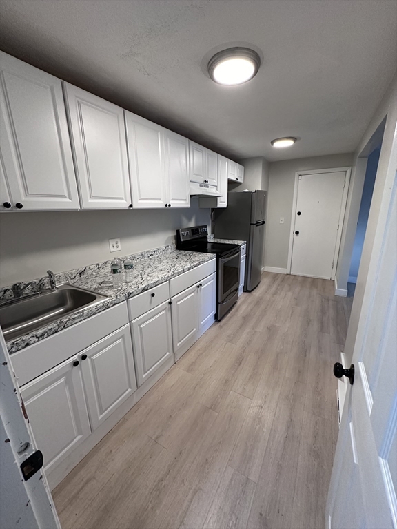 a kitchen with granite countertop a sink cabinets and stainless steel appliances