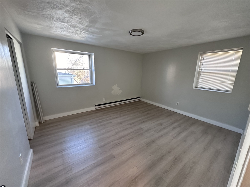 20 Hy-Sil Avenue, Unit 7 Chelsea, MA 02151 - Photo 4 of 9 an empty room with wooden floor and windows