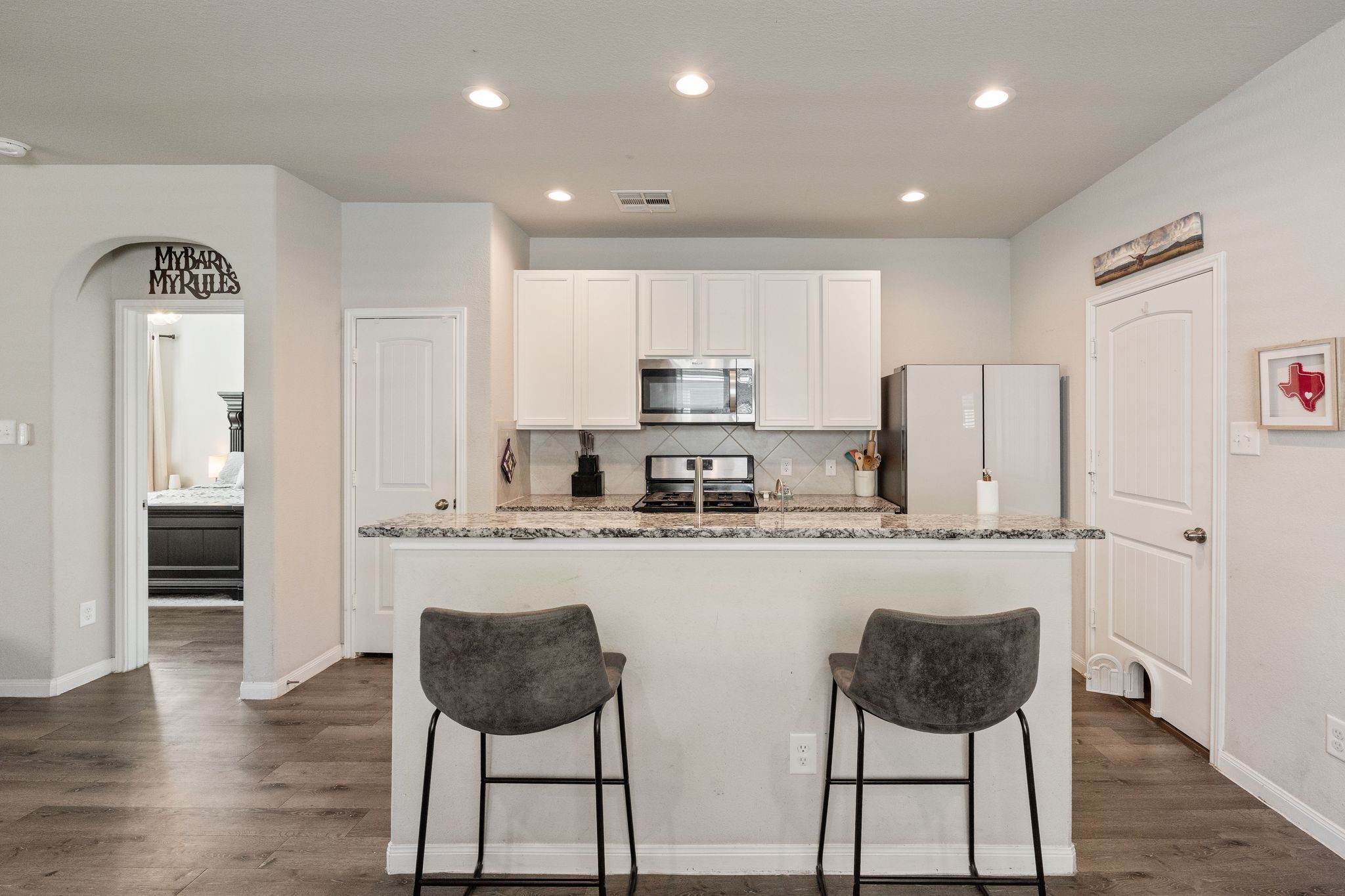 2221 Raider Drive Conroe, TX 77301 - Photo 11 of 42 a kitchen with stainless steel appliances granite countertop a stove a sink a refrigerator white cabinets and wooden floor