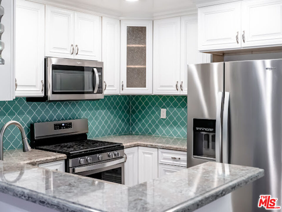 15511 Sherman Way, Unit 17 Van Nuys, CA 91406 - Photo 26 of 47 a kitchen with granite countertop a stove and a microwave