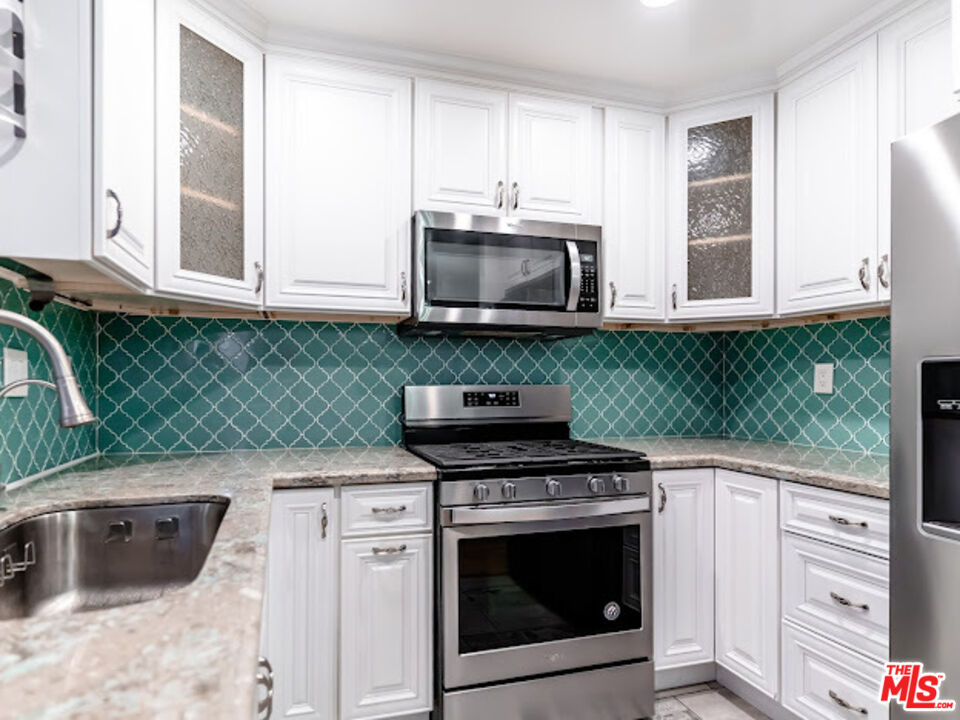15511 Sherman Way, Unit 17 Van Nuys, CA 91406 - Photo 27 of 47 a kitchen with granite countertop cabinets stainless steel appliances and a sink
