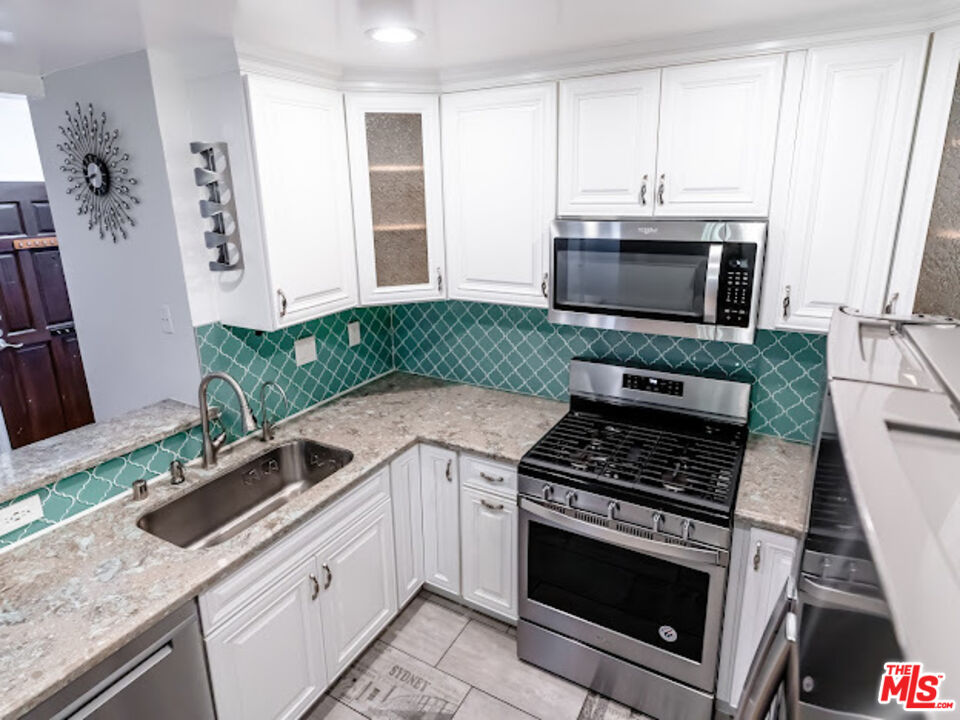15511 Sherman Way, Unit 17 Van Nuys, CA 91406 - Photo 8 of 47 a kitchen with granite countertop a stove and a microwave