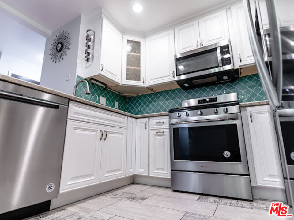 15511 Sherman Way, Unit 17 Van Nuys, CA 91406 - Photo 9 of 47 a kitchen with white cabinets and stainless steel appliances