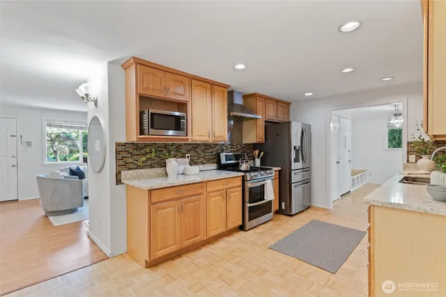 a kitchen with stainless steel appliances granite countertop a stove a sink a refrigerator and a microwave