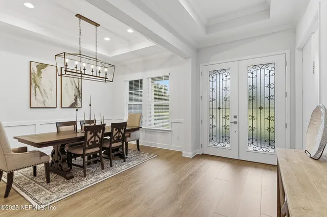 a dining room with wooden floor a chandelier a glass table and chairs
