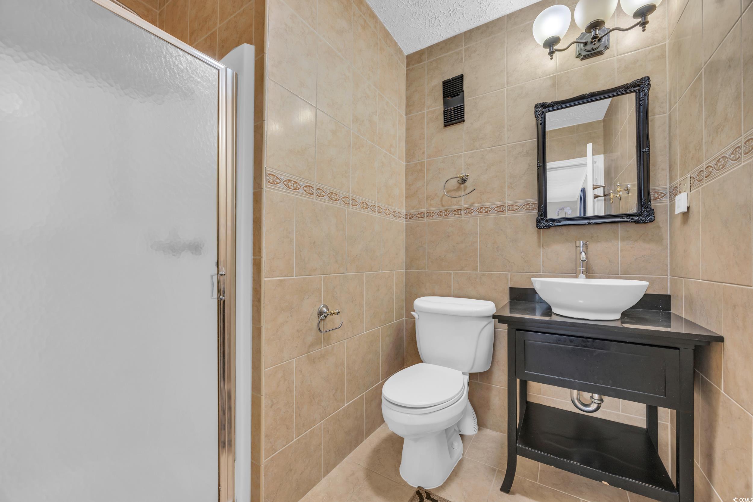 2405 South Ocean Boulevard, Unit 306 North Myrtle Beach, SC 29582 - Photo 18 of 37 Bathroom with a textured ceiling, tile walls, and