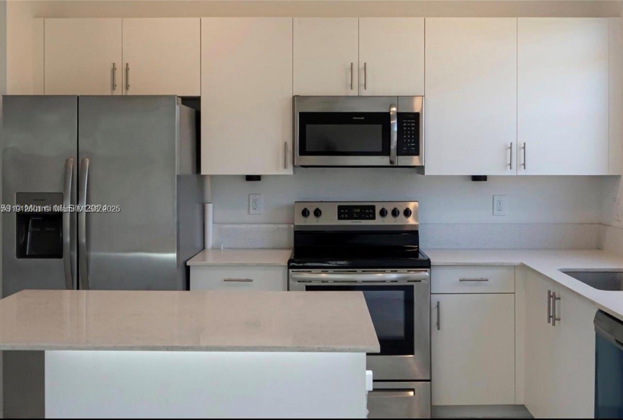 561 Northeast 208th Terrace, Unit 561 Miami, FL 33179 - Photo 20 of 31 a kitchen with stainless steel appliances a refrigerator a stove top oven a sink and cabinets