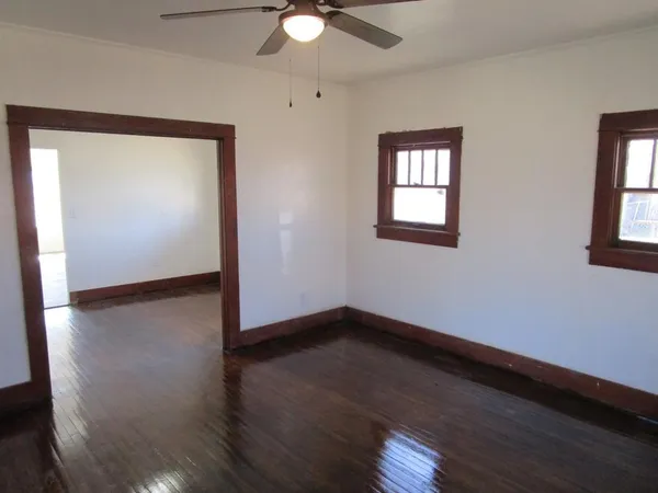 a view of an empty room with wooden floor and a window