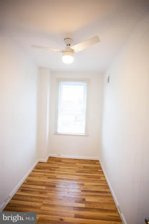 a view of an empty room with wooden floor and window
