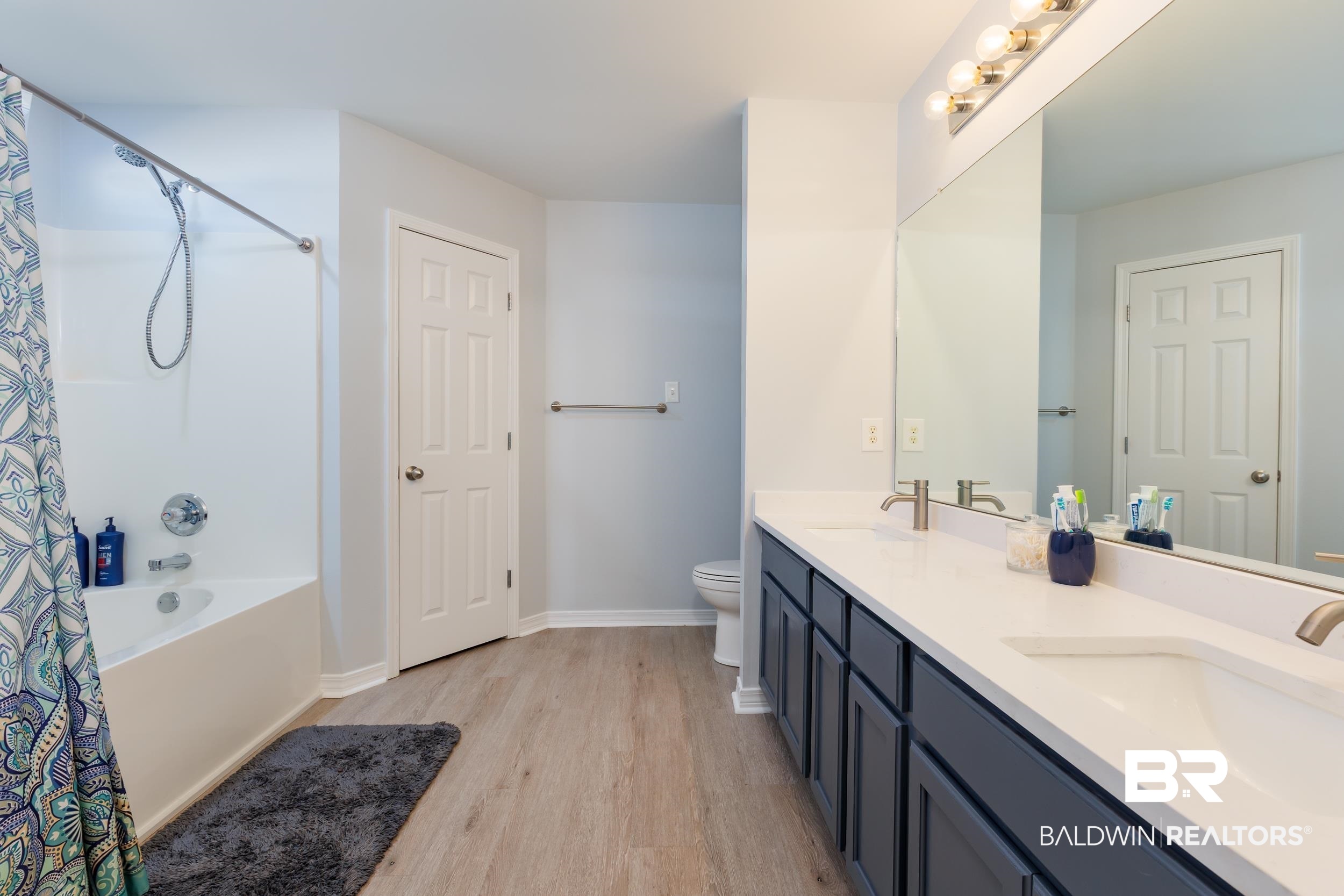 16227 Zenith Drive Loxley, AL 36551 - Photo 13 of 23 Bathroom with light wood-style floors, double vanity, and shower / tub combo with curtain