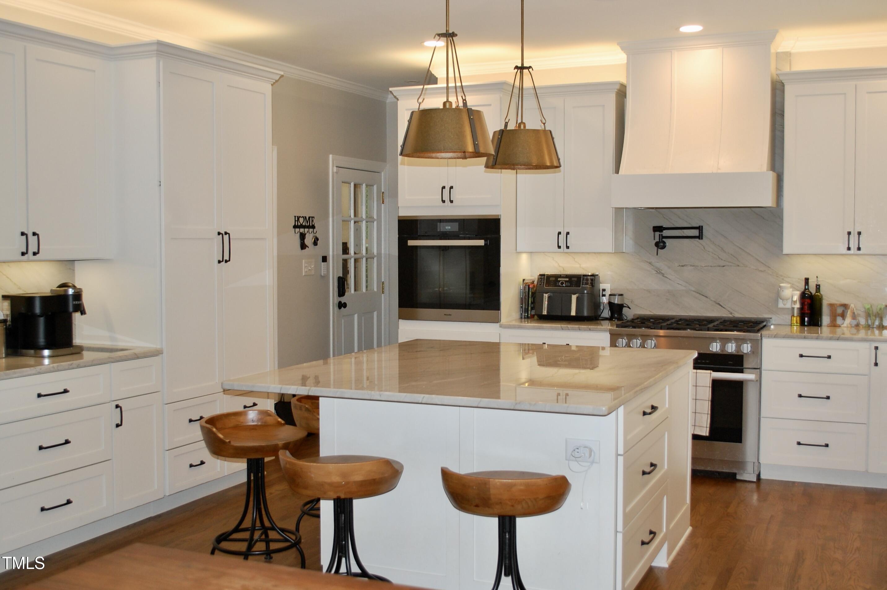 2216 Countrywood Road North Raleigh, NC 27615 - Photo 6 of 22 a kitchen with stainless steel appliances a stove a sink island and a refrigerator with wooden floor