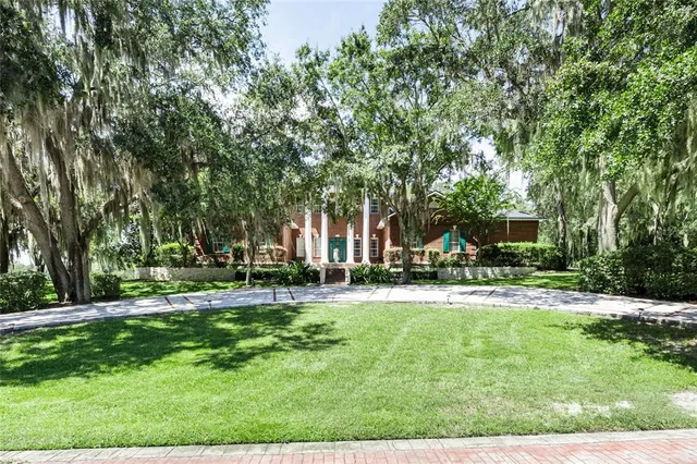 a view of a house with a big yard and large trees