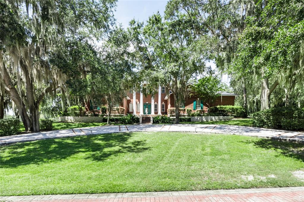 a view of a house with a big yard and large trees
