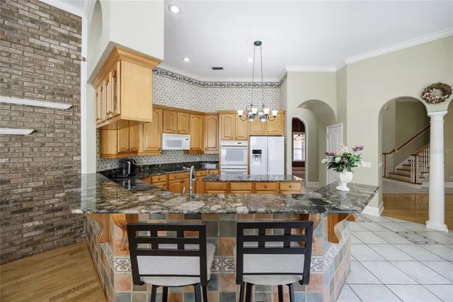 a kitchen with stainless steel appliances granite countertop a kitchen island and chairs in it