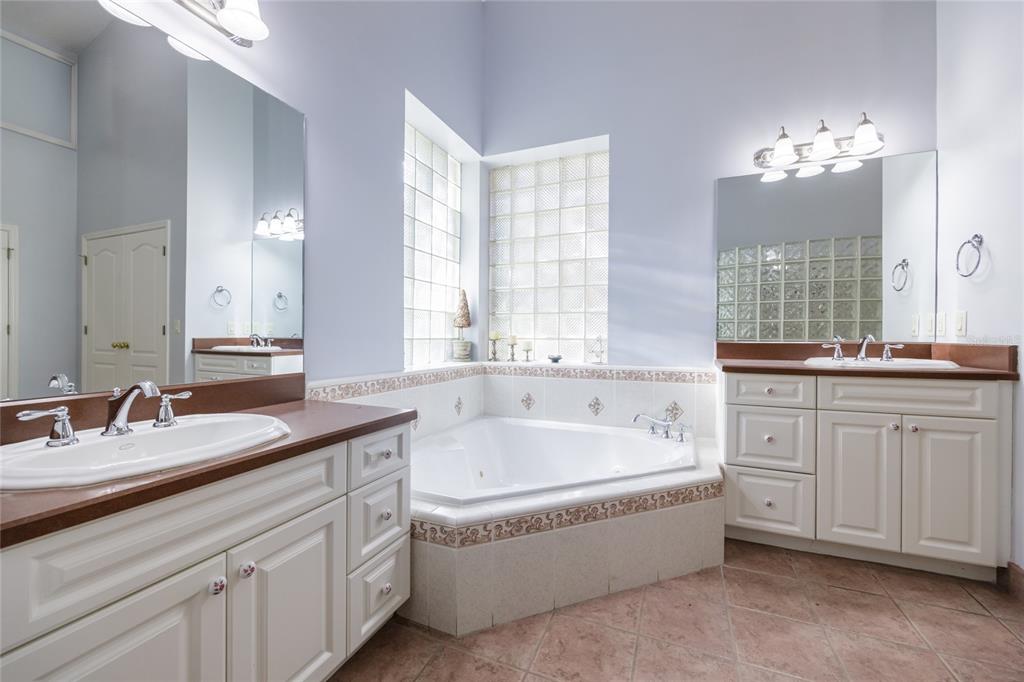 7513 Southwest 35th Way Gainesville, FL 32608 - Photo 21 of 38 a spacious en suite bathroom with a granite countertop double vanity sink a bathtub and mirror