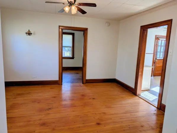 a view of an empty room with window and wooden floor