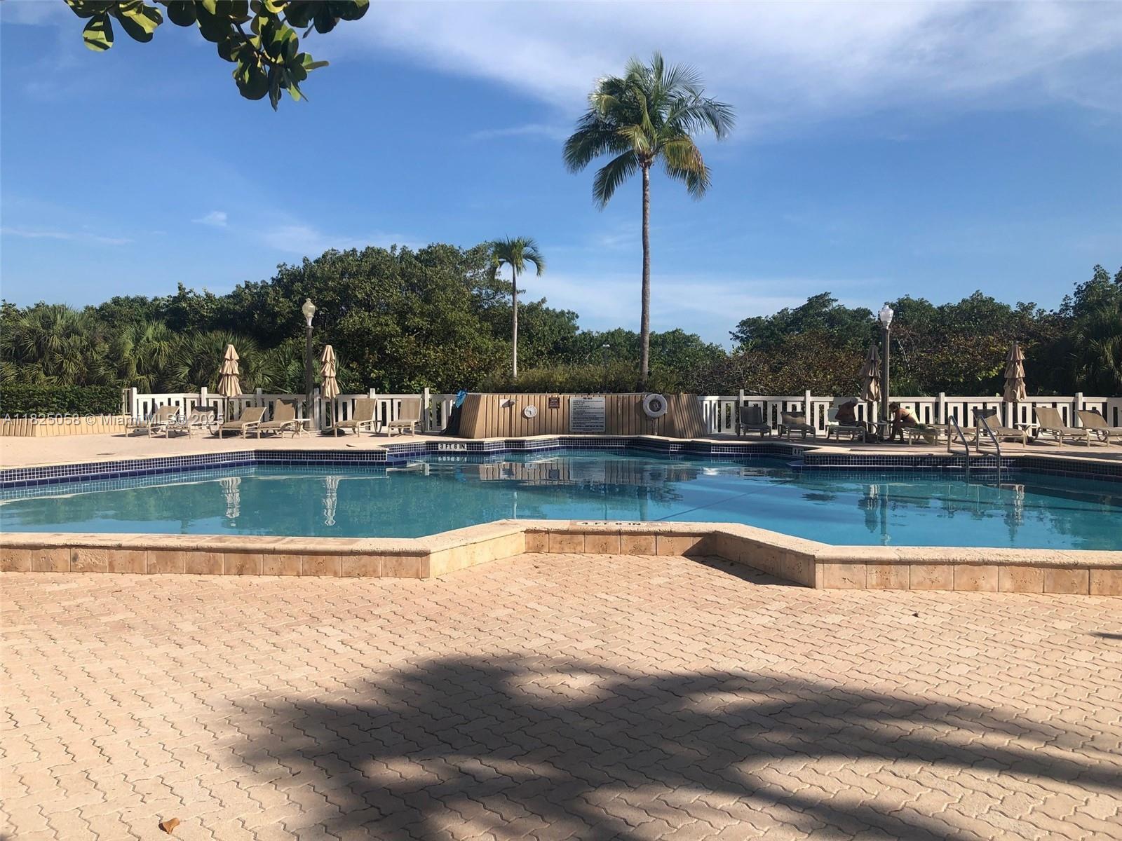 1111 Crandon Boulevard, Unit C402 Key Biscayne, FL 33149 - Photo 26 of 32 a view of a swimming pool and trees in the background