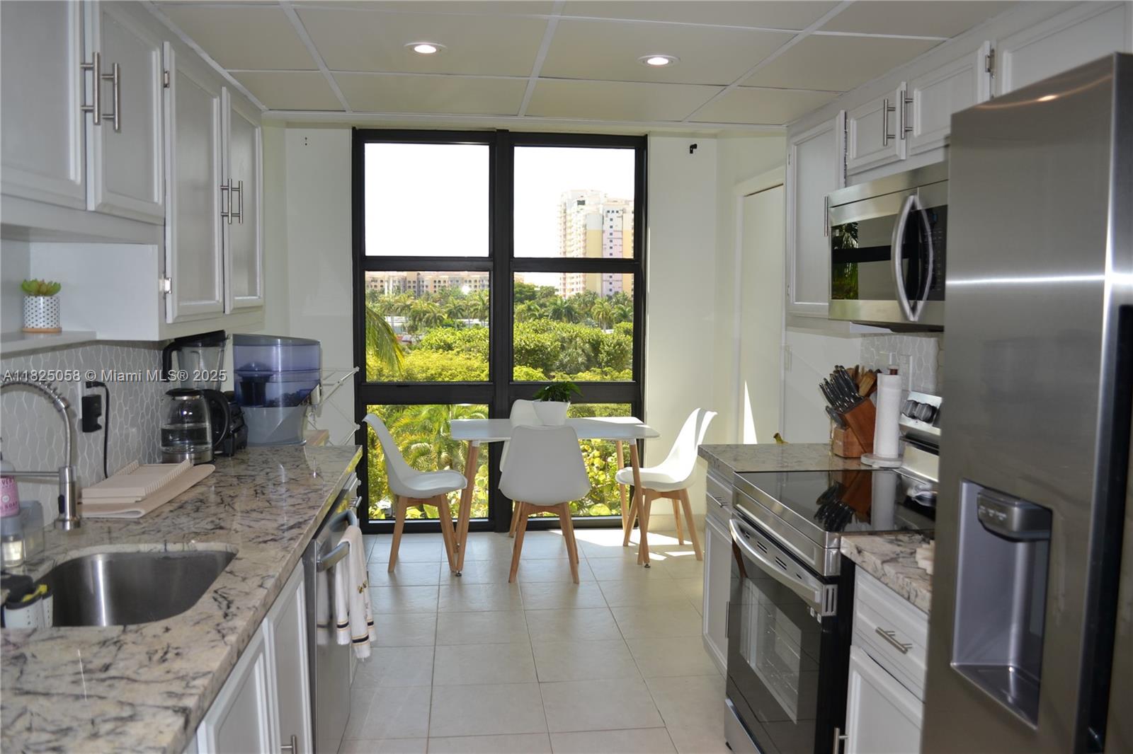 1111 Crandon Boulevard, Unit C402 Key Biscayne, FL 33149 - Photo 6 of 32 a kitchen with stainless steel appliances granite countertop a refrigerator stove microwave and sink