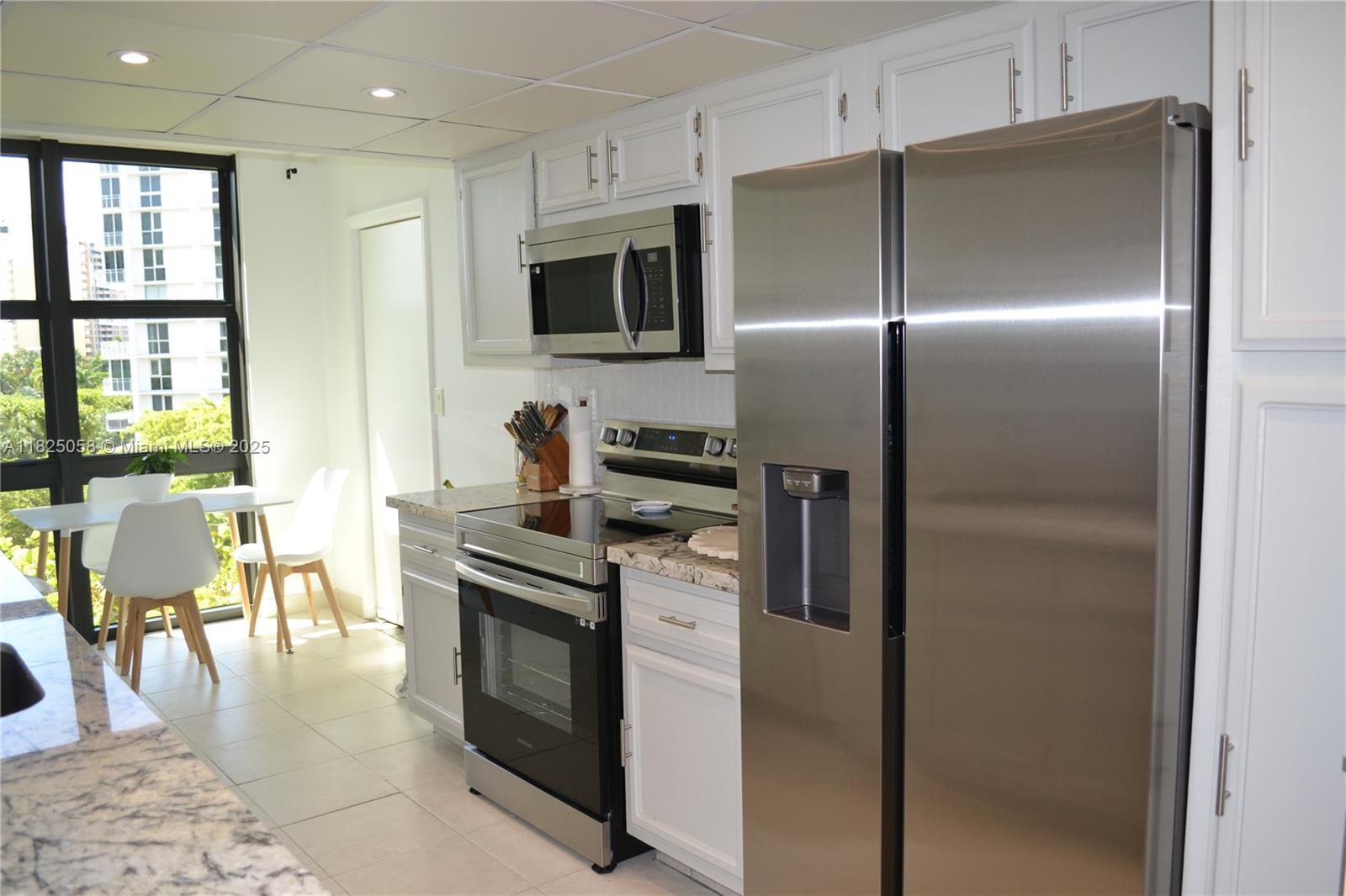 1111 Crandon Boulevard, Unit C402 Key Biscayne, FL 33149 - Photo 7 of 32 a kitchen with stainless steel appliances granite countertop a refrigerator a stove a dining table and chairs with wooden floor