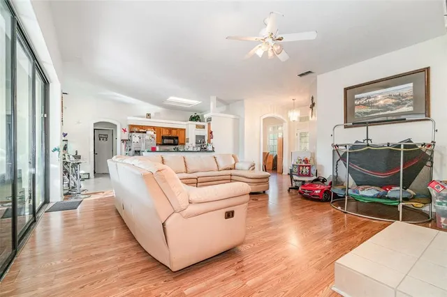 a living room with furniture a flat screen tv and a ceiling fan
