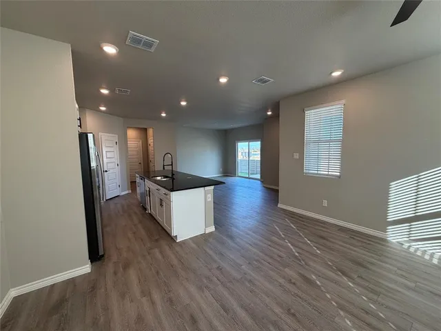 a large kitchen with stainless steel appliances a large counter top a wooden floor and a window