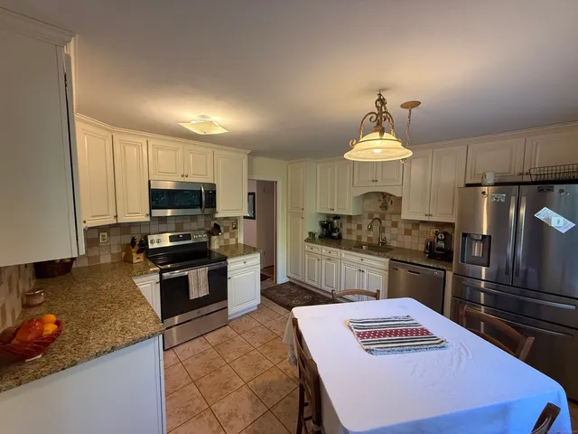 a kitchen with kitchen island granite countertop a stove refrigerator and microwave