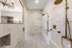 1141 East Lost Ridge Drive Washington, UT 84780 - Photo 66 of 108 Spacious shower featuring white marble-look wall tiles, pebble-style floor tiling, and dual brass-finish shower systems