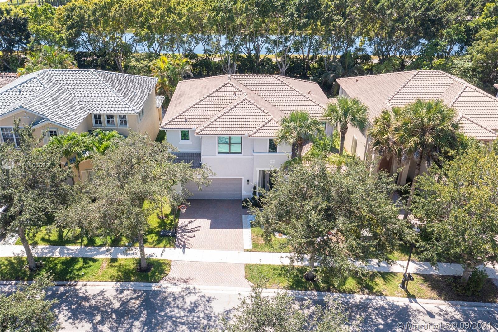 19124 Seneca Avenue Weston, FL 33332 - Photo 37 of 38 a view of a white house next to a yard with plants and trees