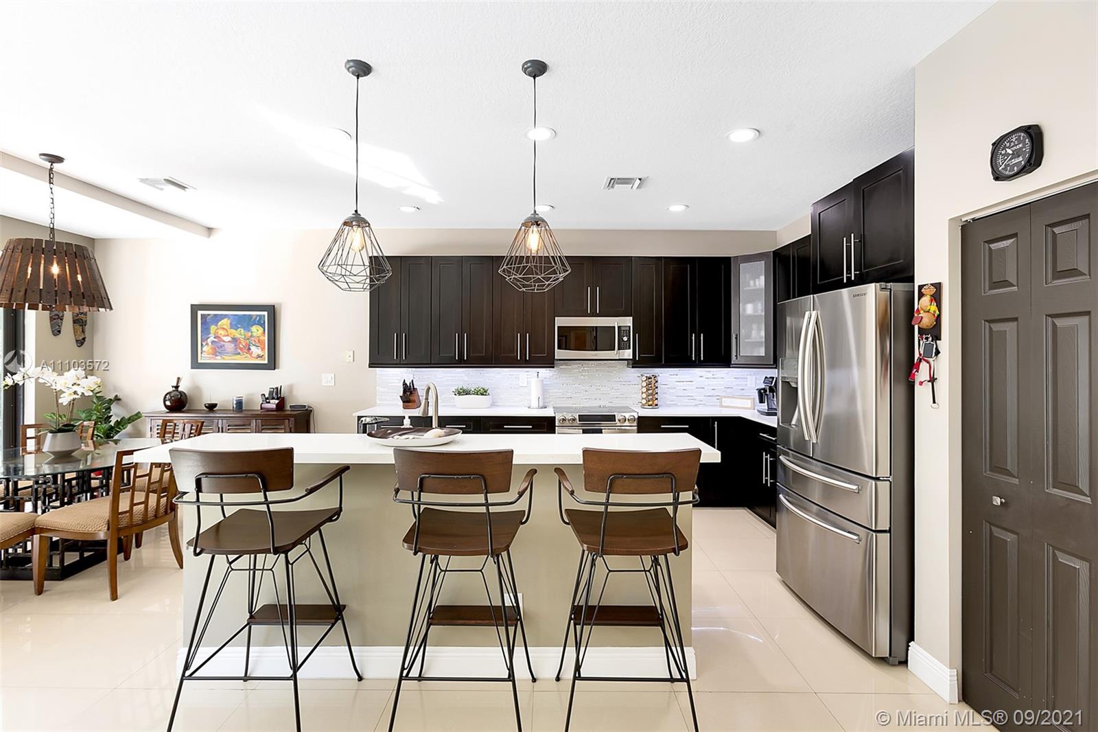 19124 Seneca Avenue Weston, FL 33332 - Photo 7 of 38 a kitchen with a table chairs refrigerator and cabinets