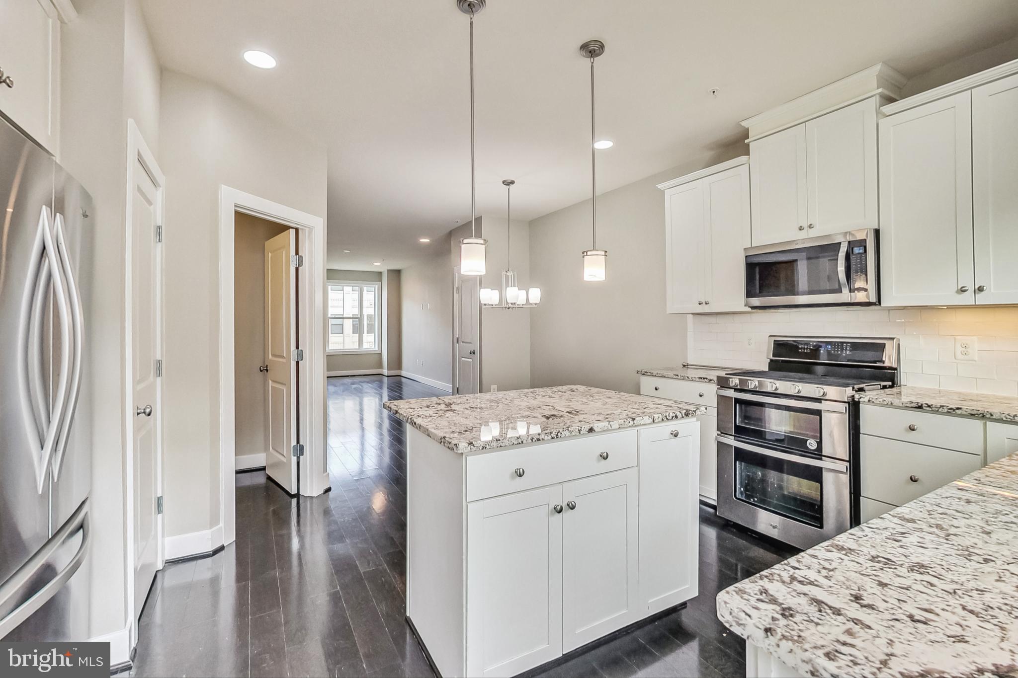 12609 Macaulay Street Silver Spring, MD 20906 - Photo 12 of 38 a kitchen with stainless steel appliances kitchen island granite countertop a stove a sink and a refrigerator