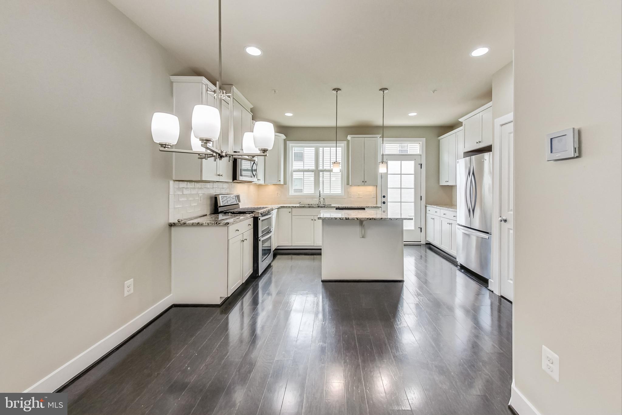 12609 Macaulay Street Silver Spring, MD 20906 - Photo 8 of 38 a large white kitchen with lots of counter space wooden floor and appliances